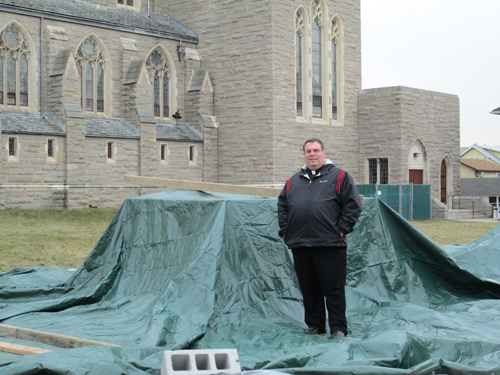 Photo by Ron LeirThe Rev. Joseph Mancini stands by tarpaulin-covered pedestal where Four Chaplains monument will rest.