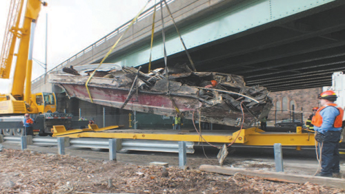 Photo courtesy Chris Brooks From top.: PVSC excavator re-positions boat, then crane begins to lift vessel, and deposits mangled remains into flatbed trailer under highway.