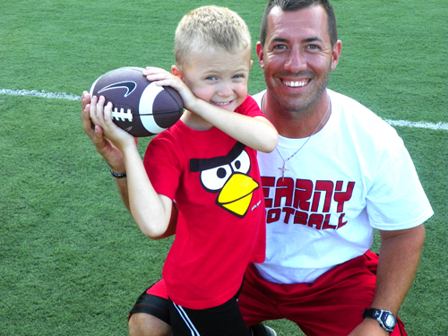 Photo by Jim Hague New Kearny head football coach Nick Edwards shows 6-year-old Alick Krzanowski how to throw a football during the Kearny football camp held last week at the high school.