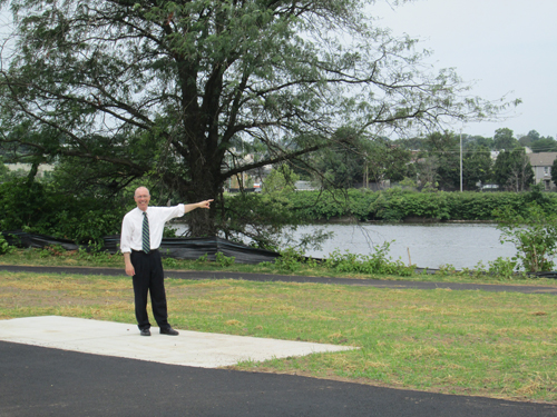 Photo by Ron Leir Mayor Alberto Santos gestures to a section of the future Frank Cardoza Park and the Passaic River just beyond.