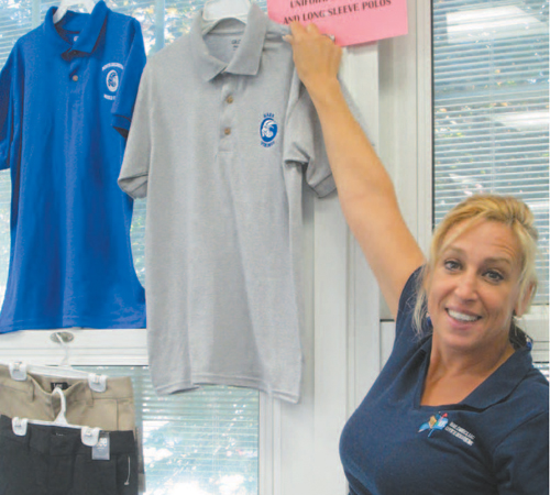 Photo by Ron Leir Mail Direct owner Michele Cimicata displays samples of the blue and grey polo shirts North Arlington students must begin wearing in Sept ember
