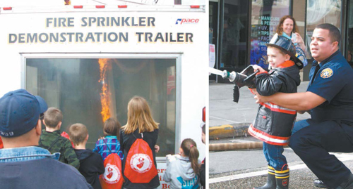 Photos courtesy KFD (Left) At KFD Open House, a close-up (but safe) look at fire control. (Right) Caden Willams, 4 (who arriived in his own turnout gear) mans a hose with help of FF Juan Barroso. Watching is Caden’s proud mom, Shannon.