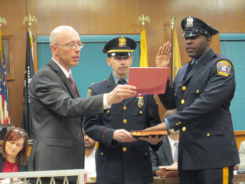 Photo by Ron Leir Jordenson Jean is sworn in by Mayor Alberto Santos as new member of the Police Department as Police Chief John Dowie assists with Bible.